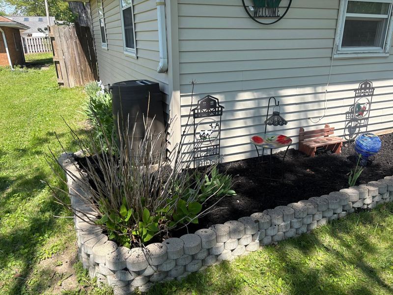 Mulch bed with a gray block border along the side of a house